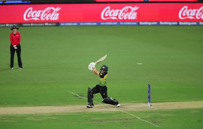 a photo of a cricket player at bat with Coca-Cola sponsorship in the background